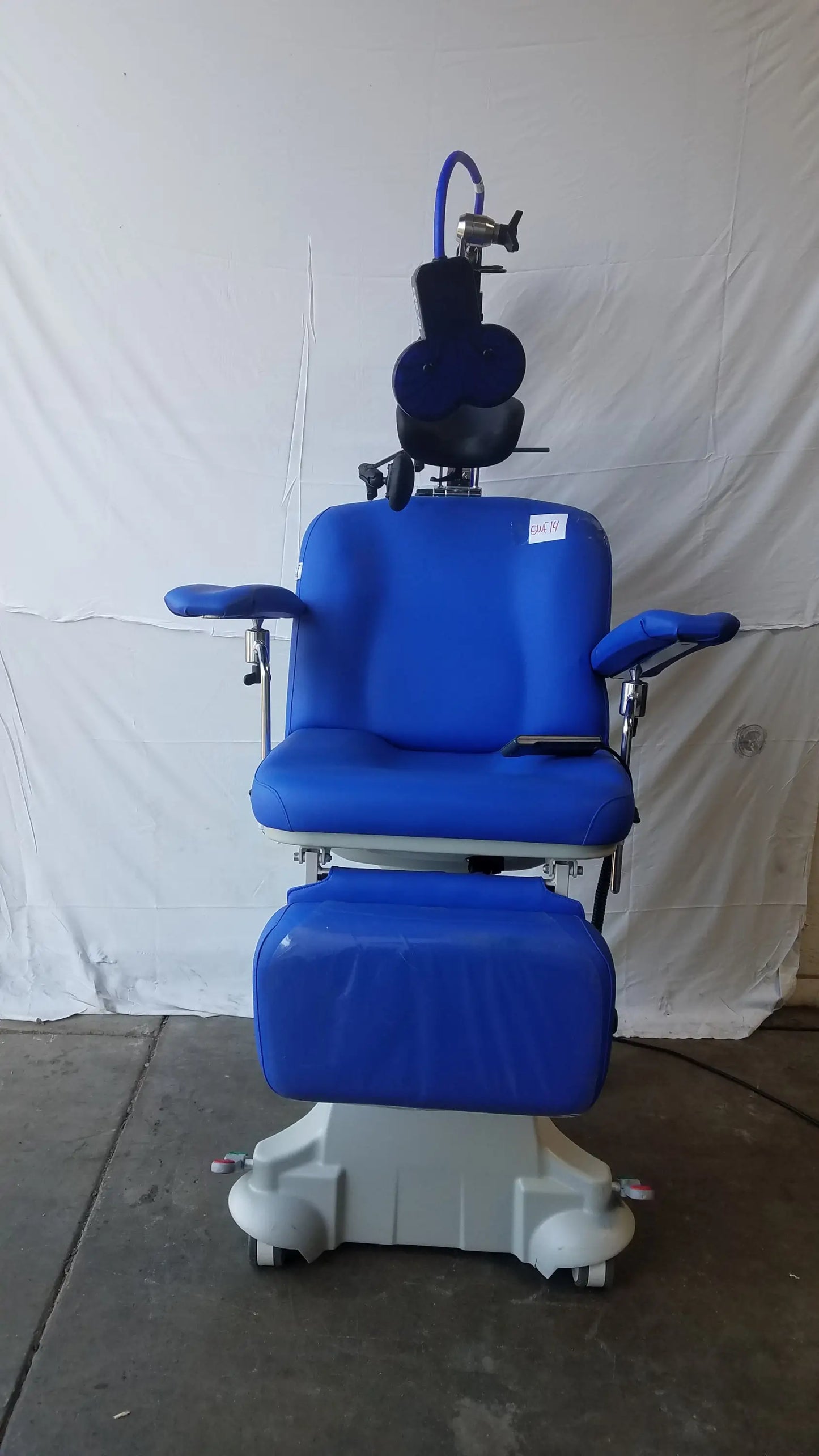 Blue padded magstim tms therapy chair with articulating arm stimulation coil gray wheeled base and adjustable headrest