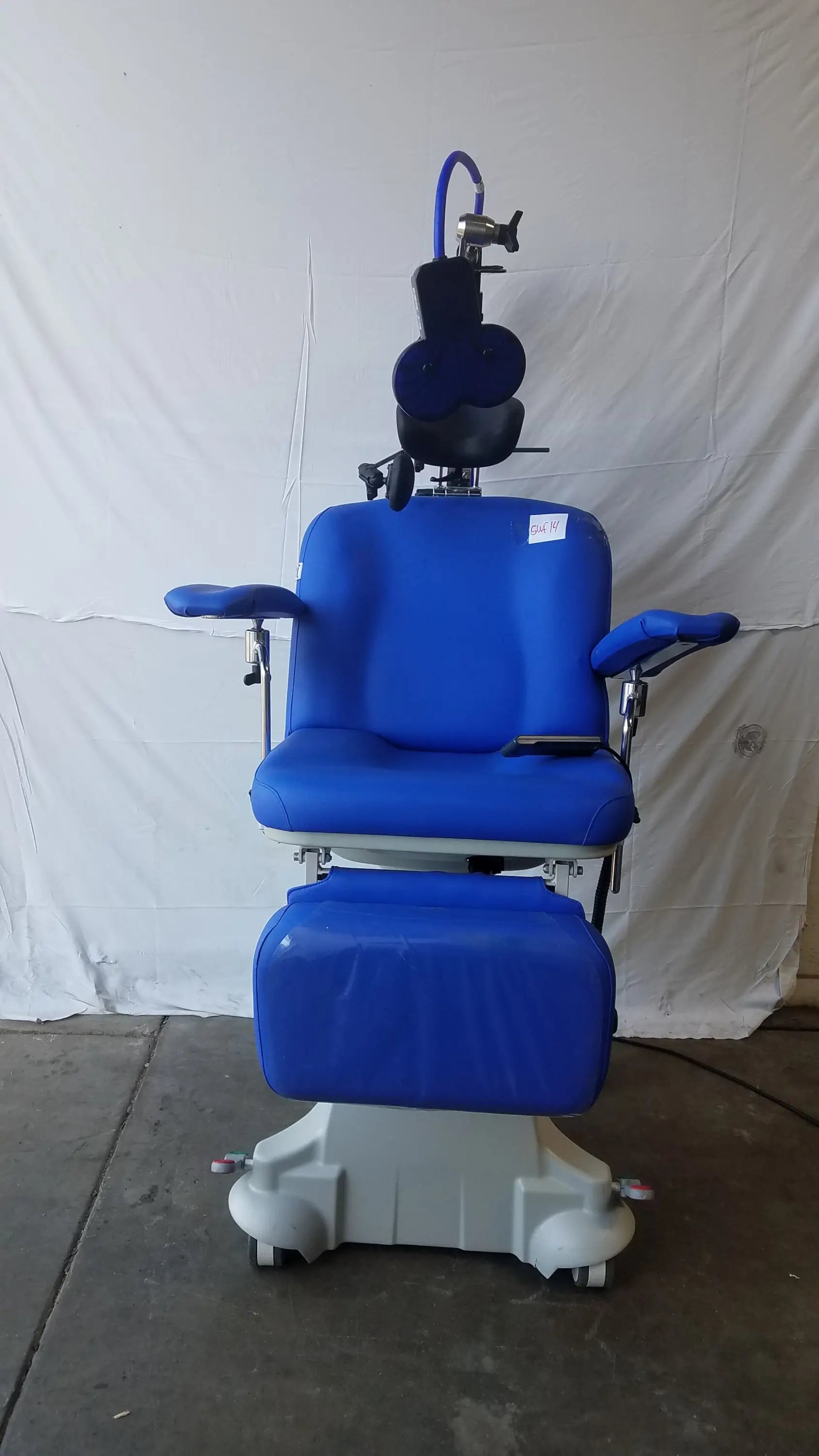 Blue padded magstim tms therapy chair with articulating arm stimulation coil gray wheeled base and adjustable headrest