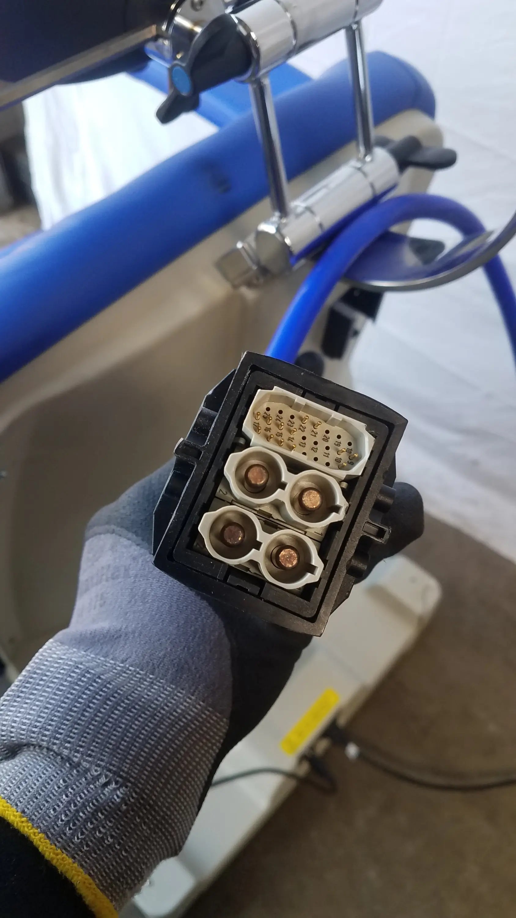 Black plastic automotive connector with four copper terminals and white socket on the back of magstim tms therapy chair articulating arm and stimulation coil