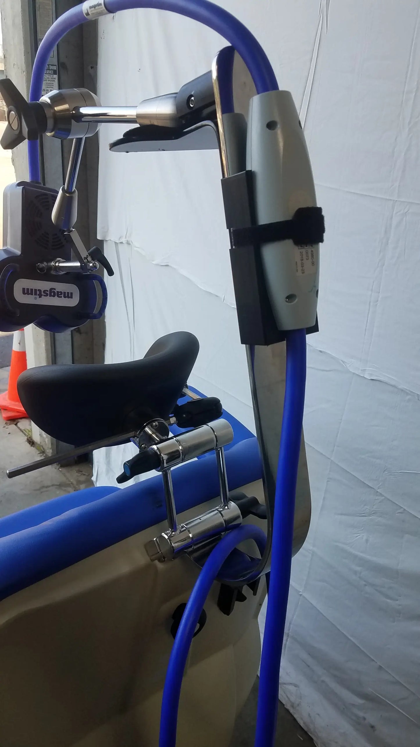 Blue and silver magstim tms therapy chair with black seat featuring articulating arm and stimulation coil for treatment sessions