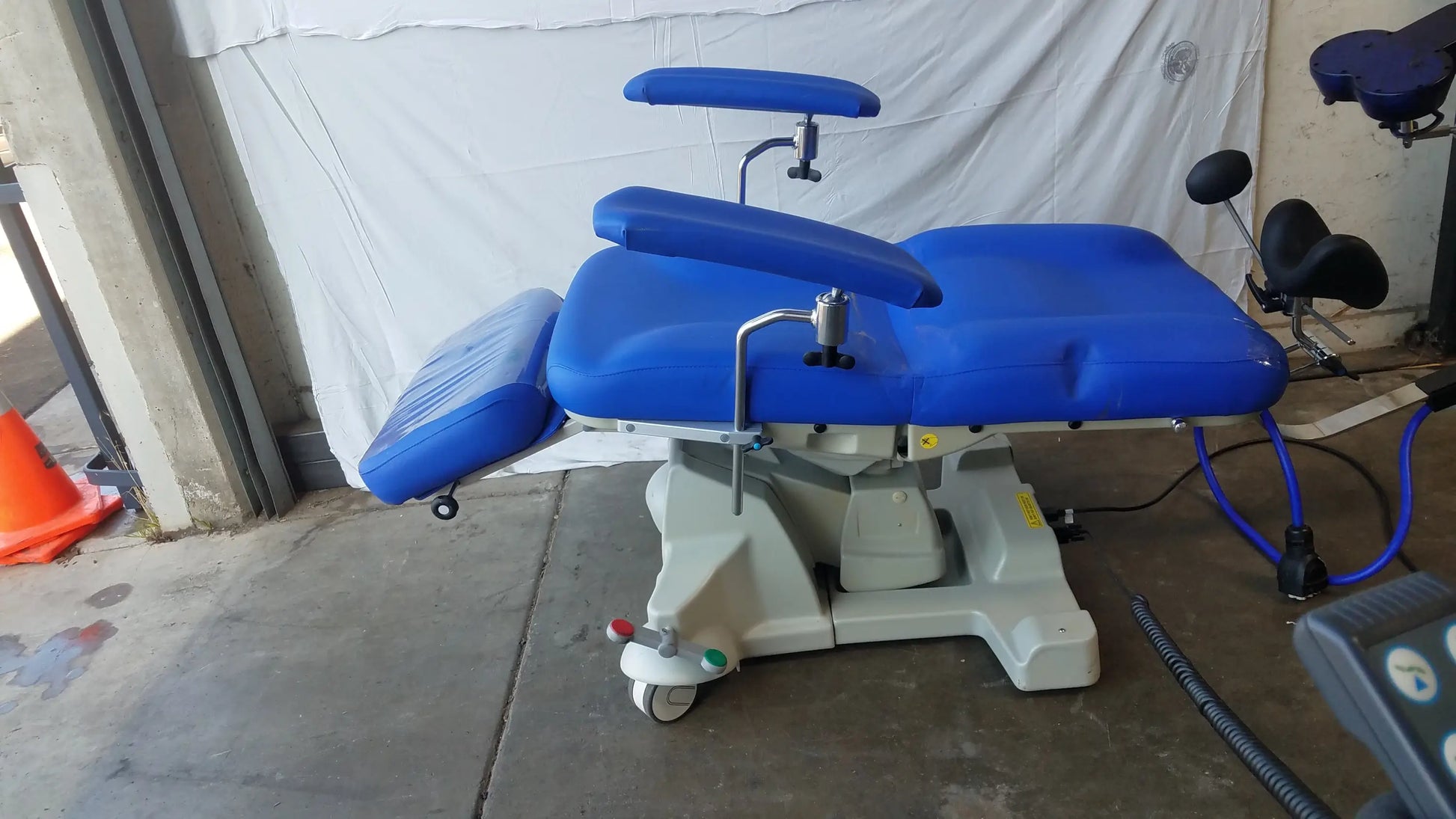 Blue padded Magstim therapy chair with articulating arm, stimulation coil, adjustable armrests, and wheels