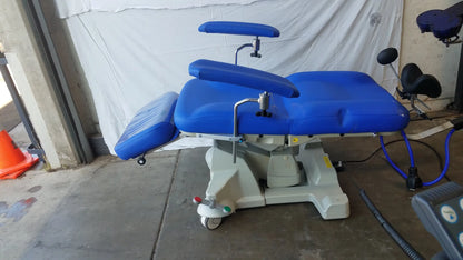 Blue padded Magstim therapy chair with articulating arm, stimulation coil, adjustable armrests, and wheels