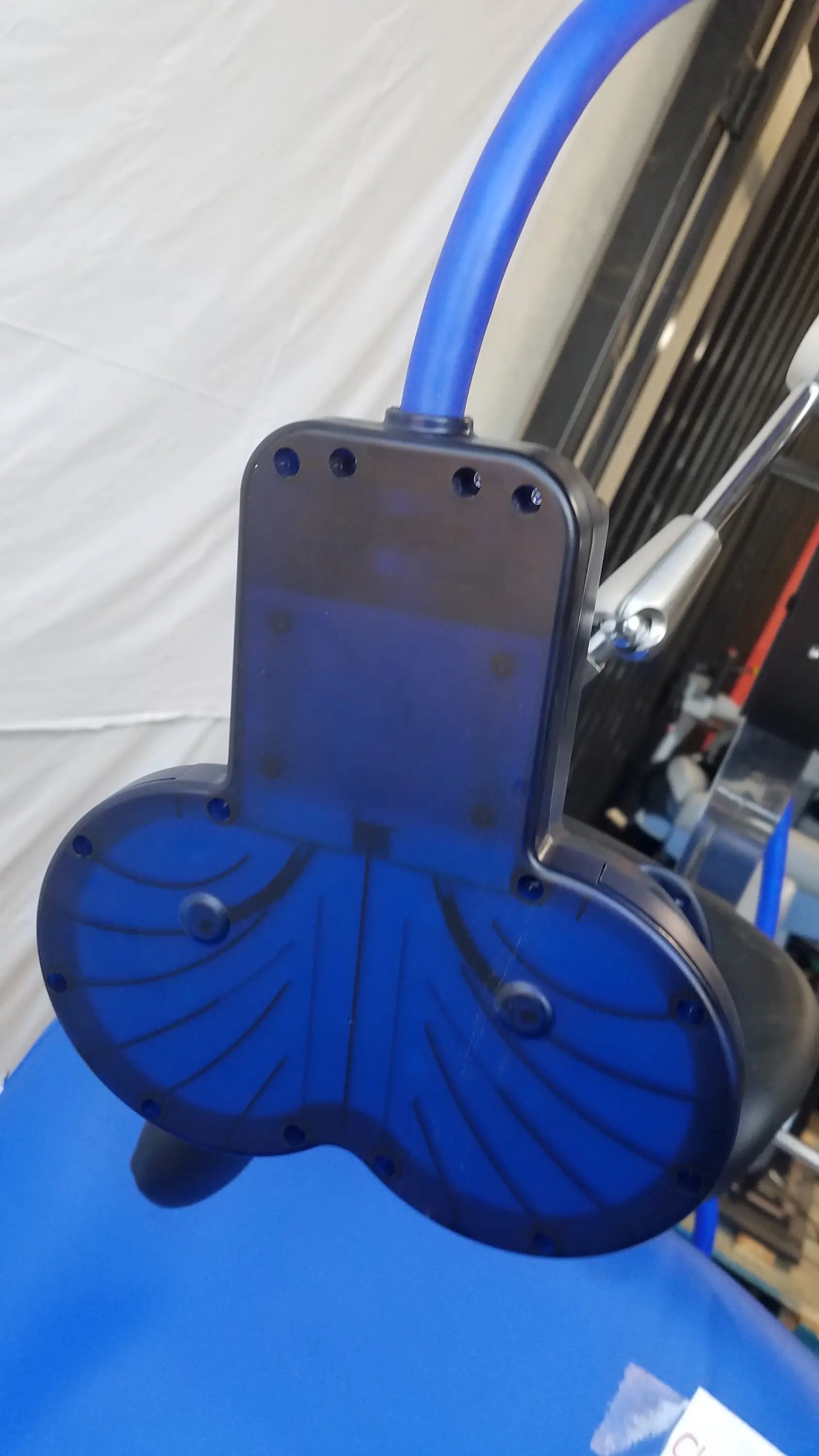Blue translucent plastic component with metallic silver bracket and blue tubing on magstim tms therapy chair articulating arm with stimulation coil