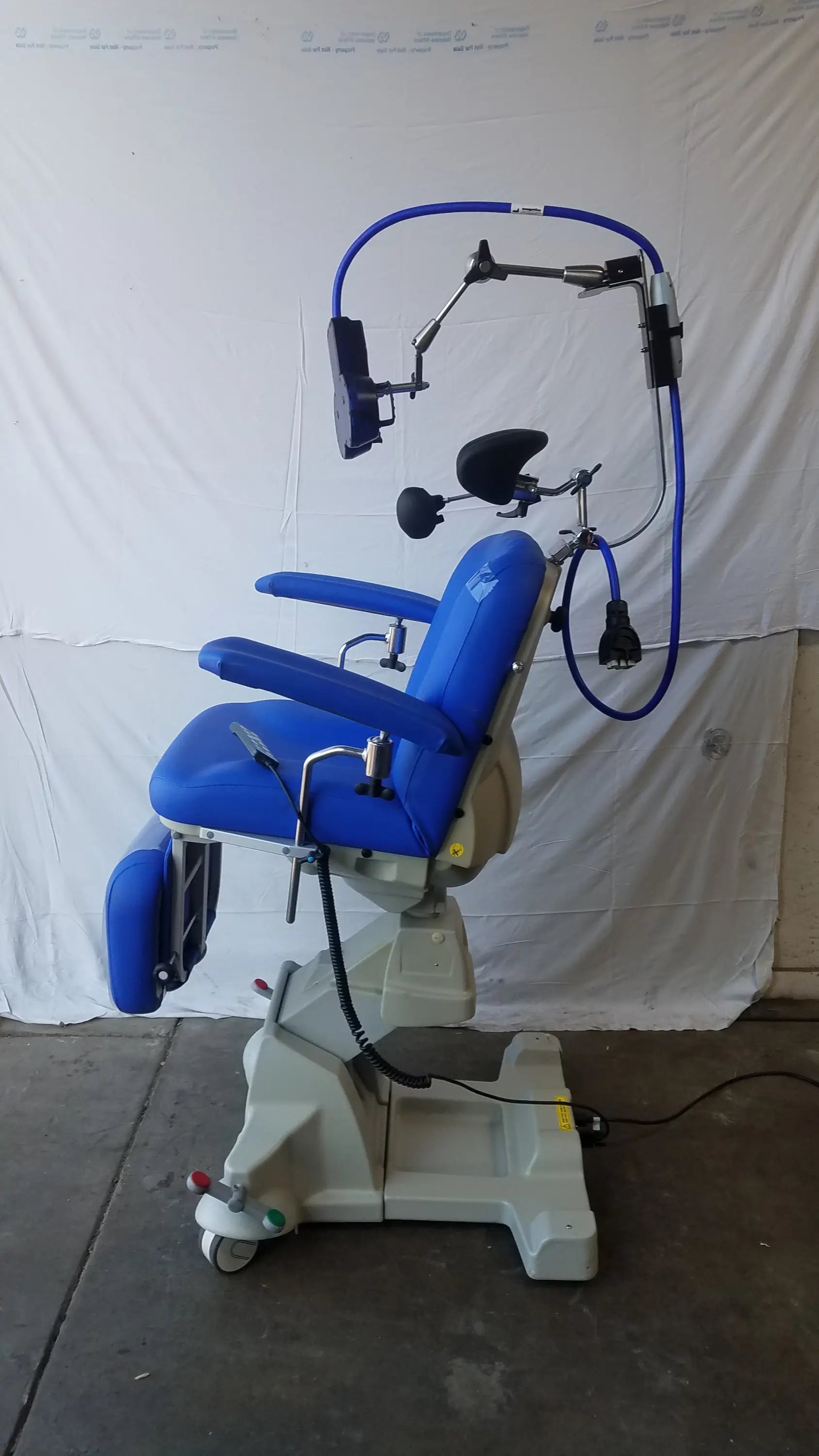 Blue Magstim TMS therapy chair with articulating arm, stimulation coil, adjustable armrests, and overhead headpiece frame