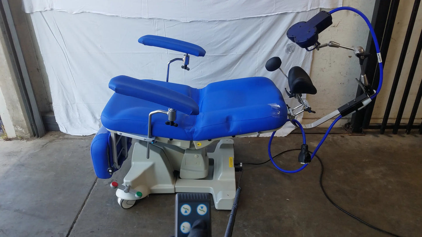 Blue Magstim TMS therapy chair with articulating arm, stimulation coil, adjustable armrests, padded seat, and gray wheeled base