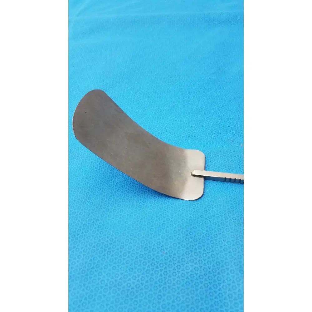 A curved metallic malleable retractor blade with a smooth reflective surface and slender handle made of stainless steel