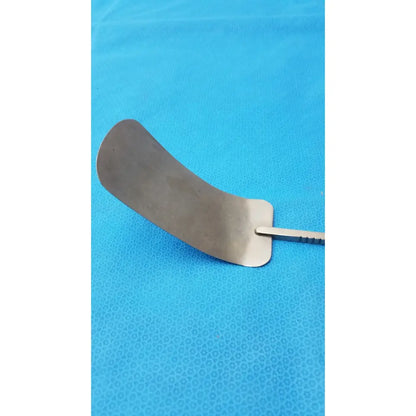 A curved metallic malleable retractor blade with a smooth reflective surface and slender handle made of stainless steel