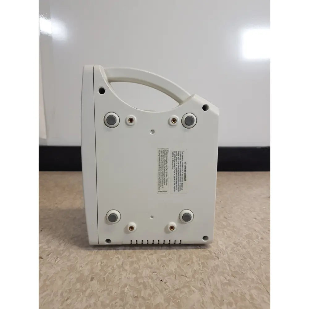 White plastic masimo set rainbow rad 87 pulse oximeter showing back with handle and multiple circular ports