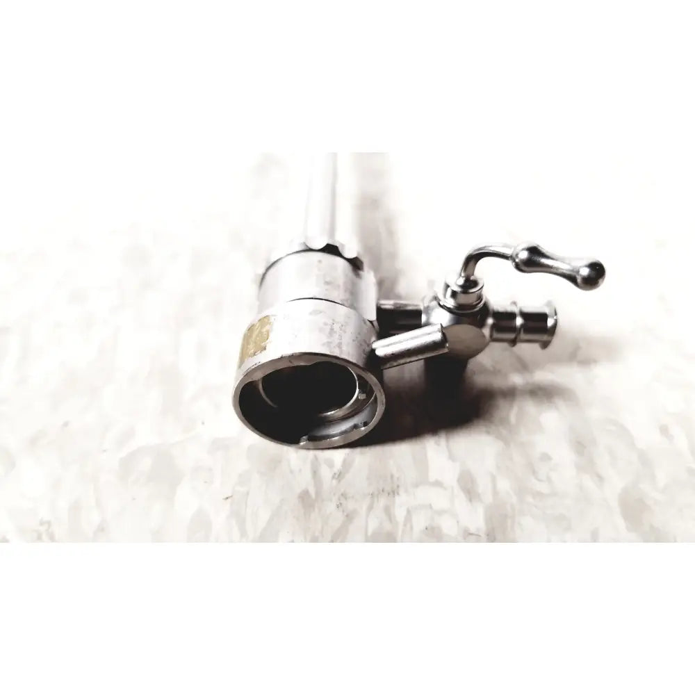A metallic cylindrical single valve endoscope sheath with a curved handle showing wear by medical horizon