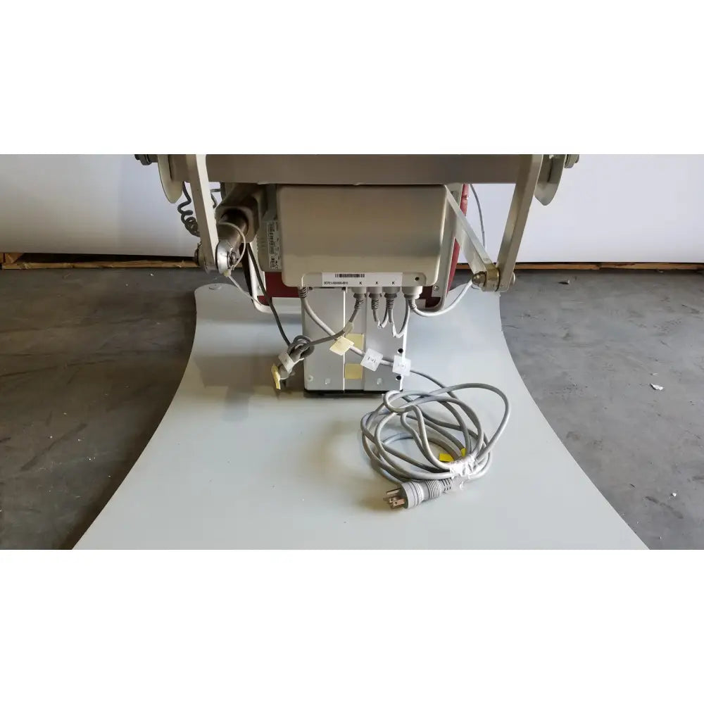 Gray electrical power cord with a three-prong plug coiled on the floor for medical power treatment chair model 8678