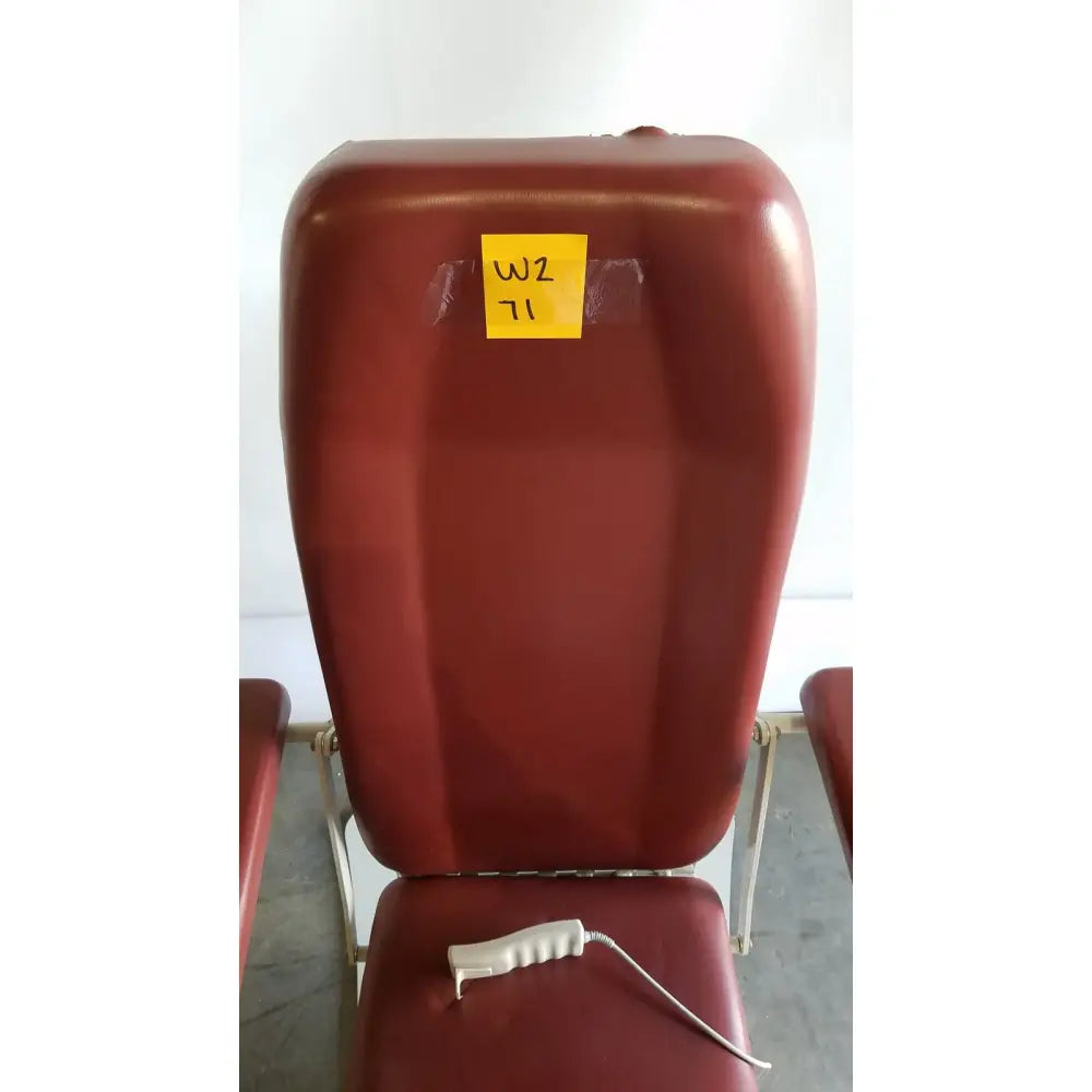 Red upholstered medical power treatment chair model 8678 with white hand control resting on seat