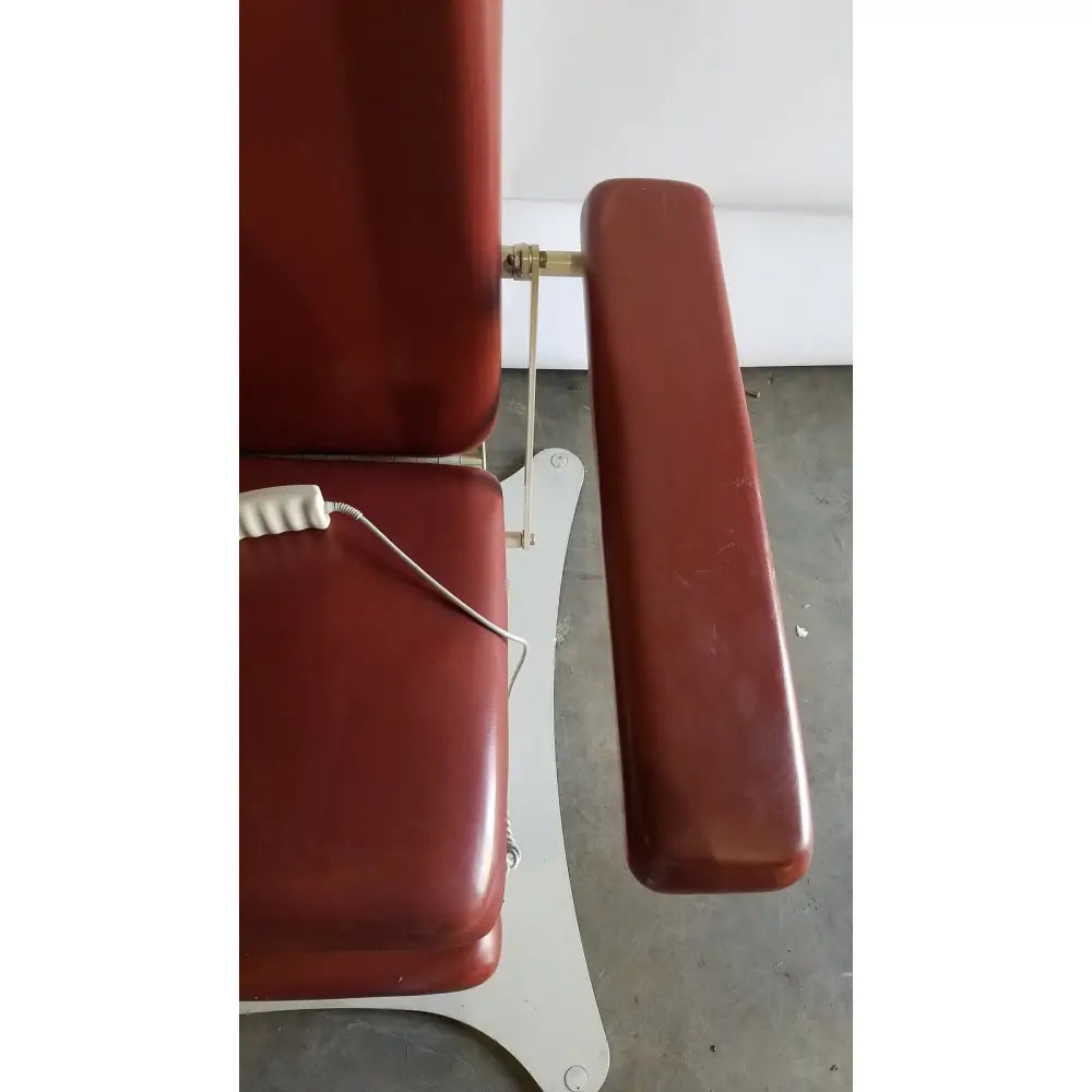 Red vinyl medical power treatment chair model 8678 with white metal base and adjustable armrest for comfort and control