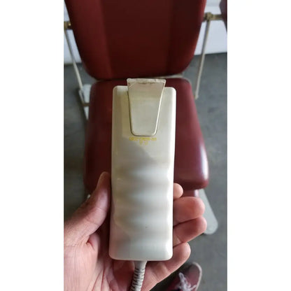 Cream-colored rectangular hand-held control unit with metallic clip and gold lettering for medical power treatment chair model 8678