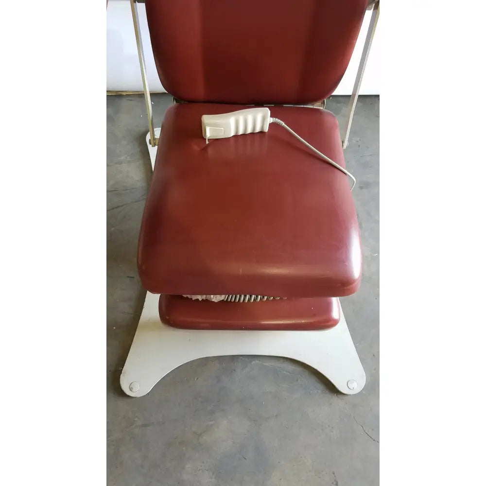 Red upholstered medical power treatment chair model 8678 with white hand control resting on its seat