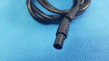 Black coiled console extension cable with matte ridged connector featuring circular indentations for surgical handpiece use in medical equipment