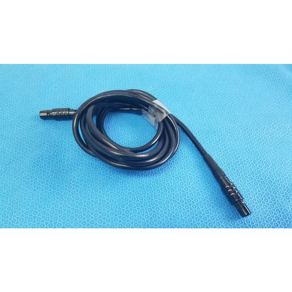 Black coiled medical surgical handpiece console extension cable with metallic connectors and clear plastic tie for medical equipment