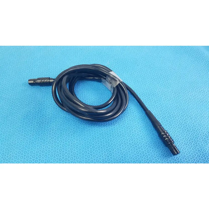 Black coiled medical surgical handpiece console extension cable with metallic connectors and clear plastic tie for medical equipment
