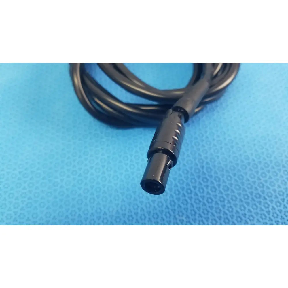 Black coiled console extension cable with matte ridged connector featuring circular indentations for surgical handpiece use in medical equipment