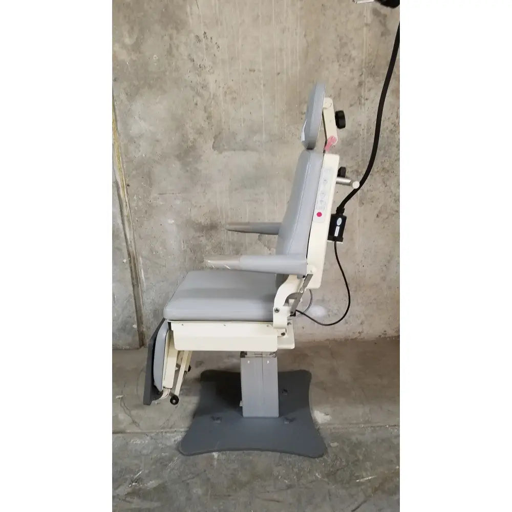 Gray and white adjustable dental chair with padded seating and footrest from medical technology industries power lift exam chair