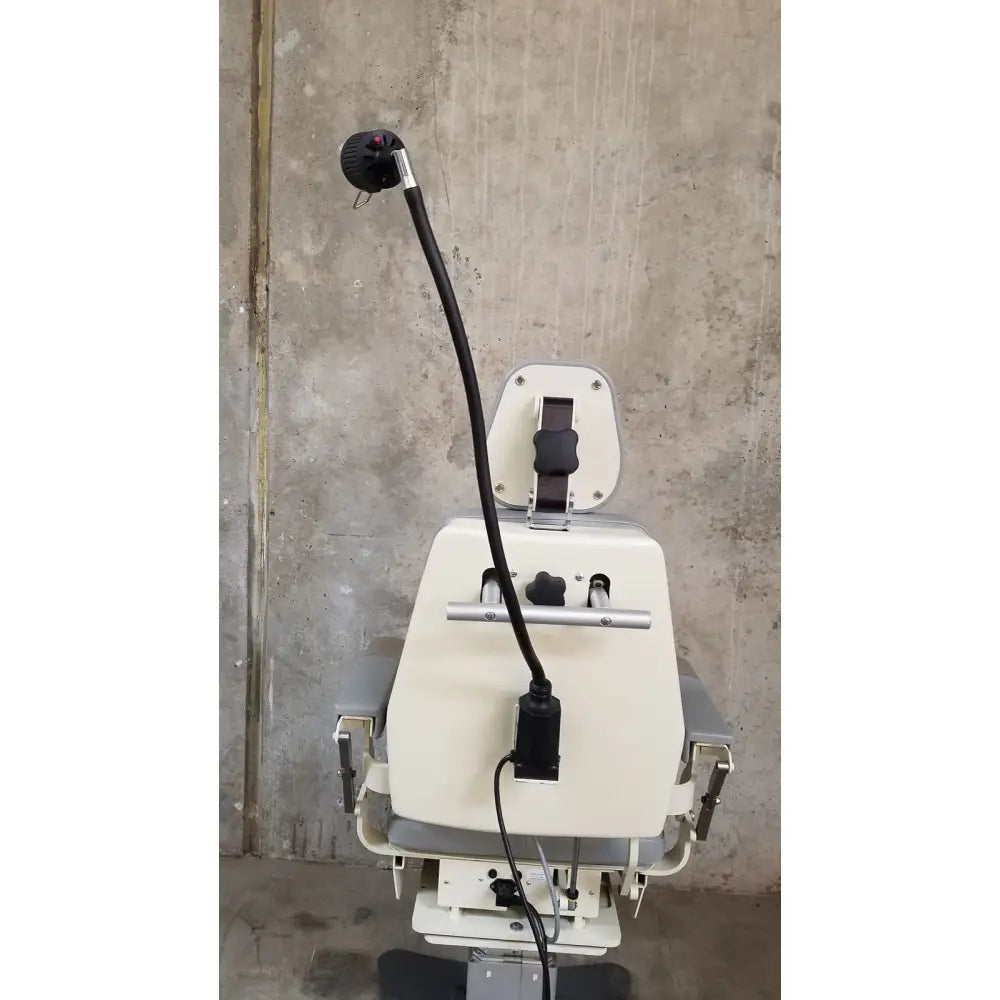 Beige medical technology industries power lift exam chair with black articulated arm and adjustable headrest for exams