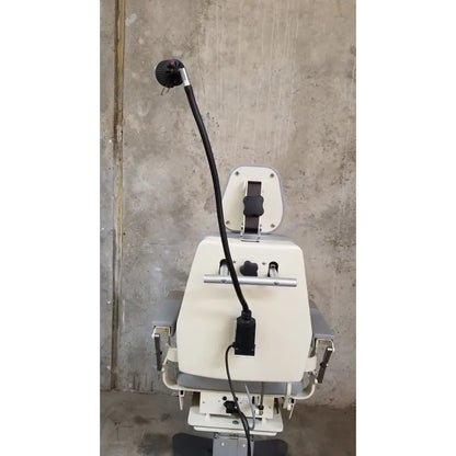 Beige medical technology industries power lift exam chair with black articulated arm and adjustable headrest for exams