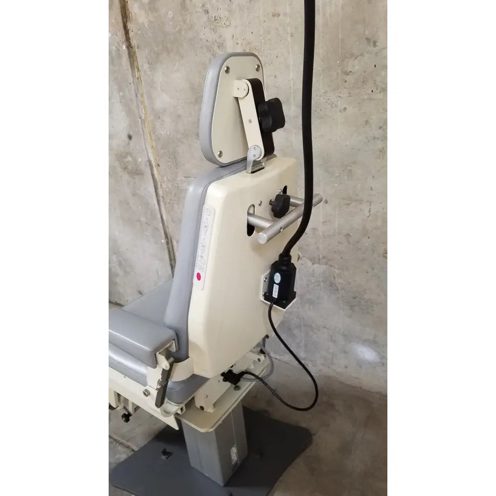 Gray and beige adjustable medical technology industries power lift exam chair with padded headrest and metal frame control knobs