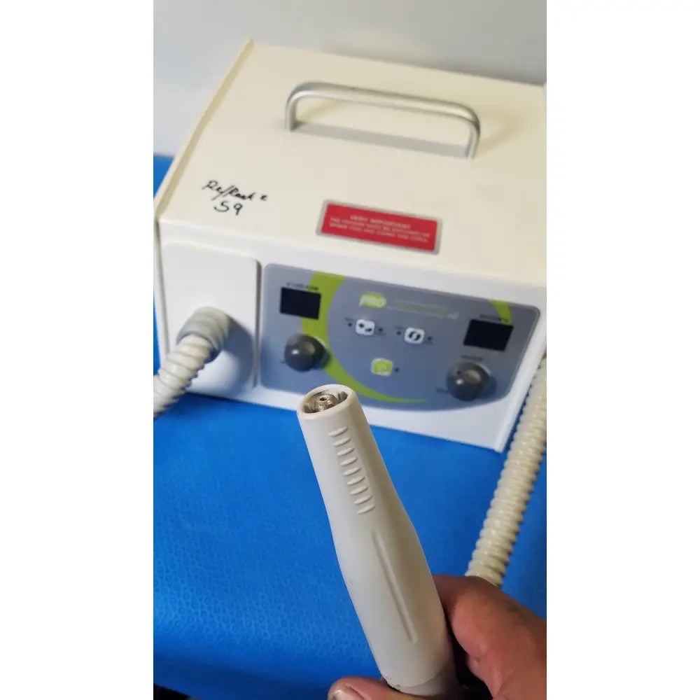 White handheld dental drill bit with textured grip and metallic tip in front of medicool pro vac file v2 dust collector vacuum system