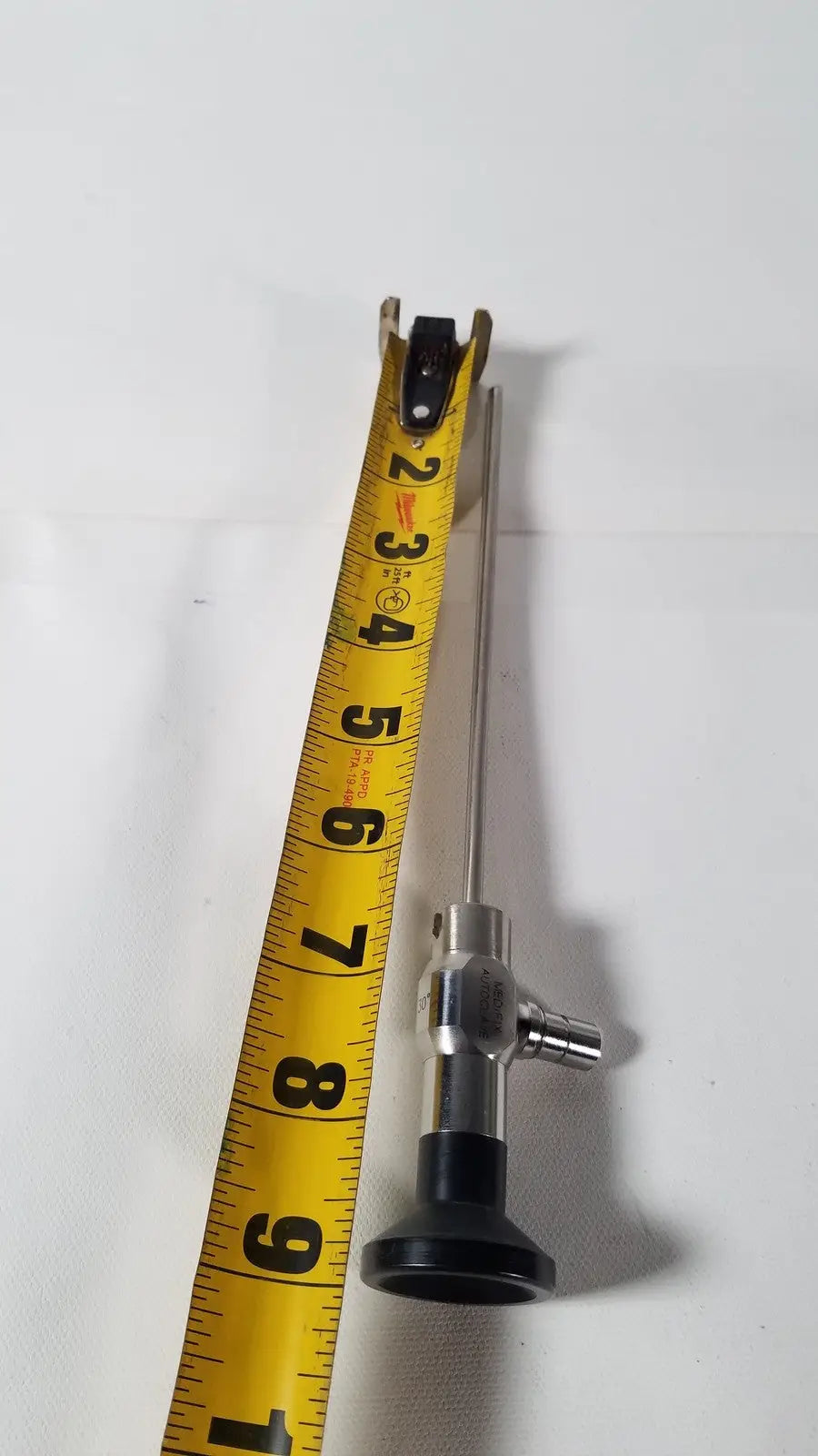 Silver medifix autoclave d-5540 30 degree endoscope with black rubberized handle and yellow measuring tape beside it