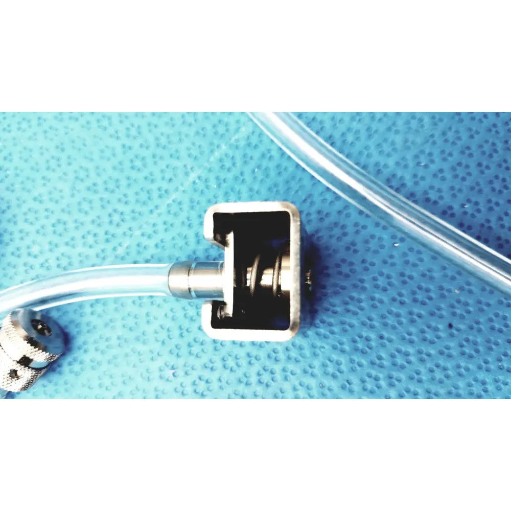 Silver metallic connector with rectangular housing and threaded fittings attached to clear tubing in medivators hook-up block unit compatible component