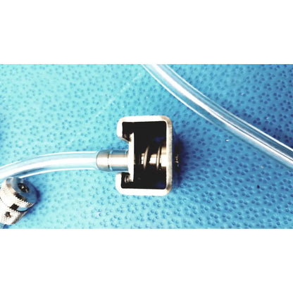 Silver metallic connector with rectangular housing and threaded fittings attached to clear tubing in medivators hook-up block unit compatible component