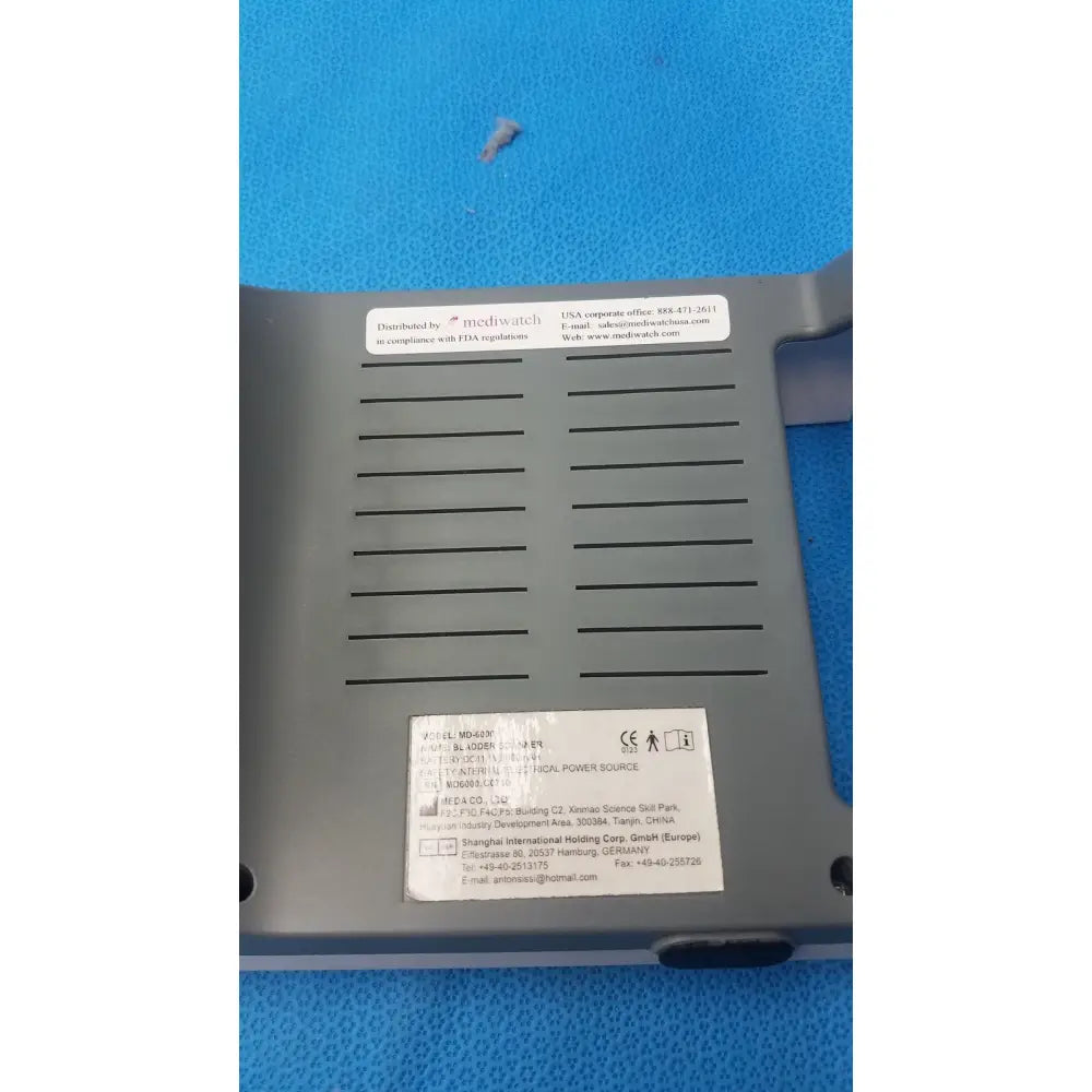 Gray plastic mediwatch md-6000 bladder scanner with horizontal slits and white label stickers on the back side