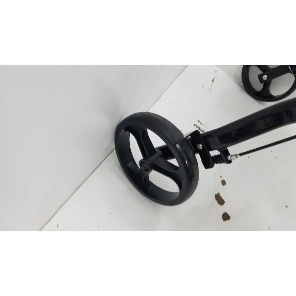 Black plastic wheel with three spokes attached to black metal frame of medline rolling walker mds8684gblkm with hand brakes
