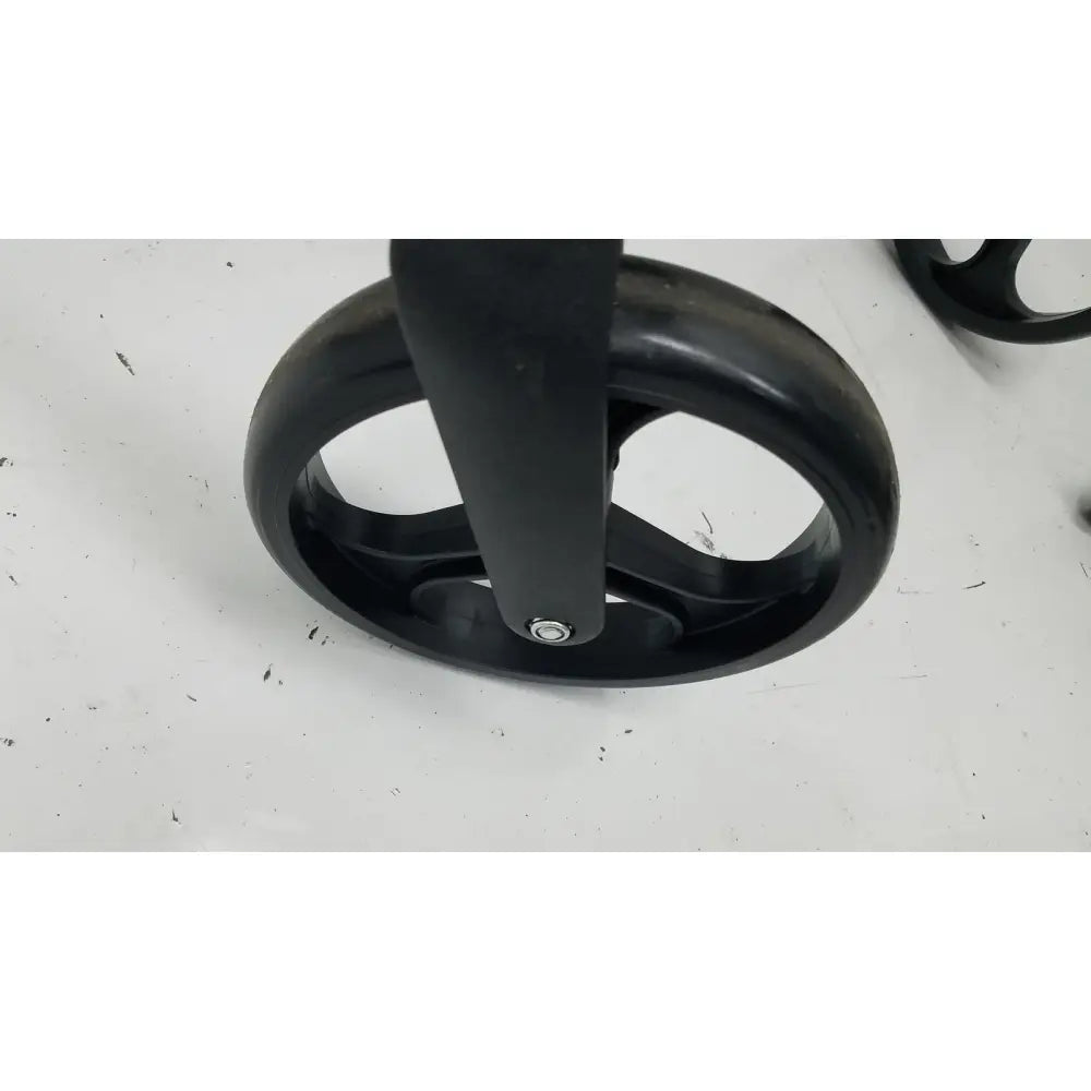 Black plastic wheel with central axle and three spokes on medline rolling walker mds8684gblkm with hand brakes