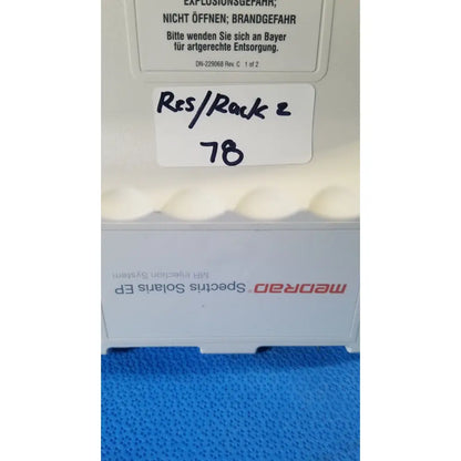 White medrad spectris solaris MR injection system battery with red branding and handwritten label on its side