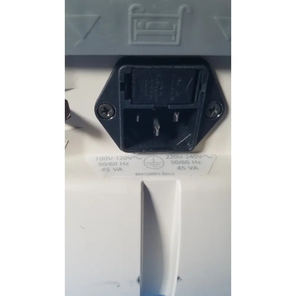 Black plastic electrical plug with two flat prongs and grounding pin on the back of a white medrad veris monitoring system casing