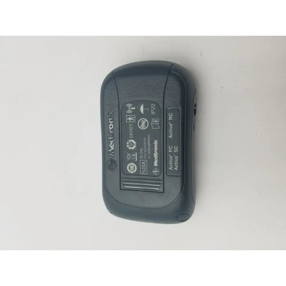 Black Medtronic Activa RC insulin pump with textured plastic casing and regulatory labels shown on back side in DBS patient programmer