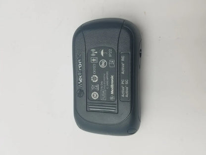 Black Medtronic Activa RC insulin pump with textured plastic casing and regulatory labels shown on back side in DBS patient programmer