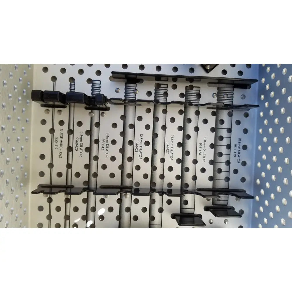 Black metal clamps with spring-loaded mechanisms on a perforated board in Medtronic 9568529 METRx II system dilators tray for reuse medical sterilization trays