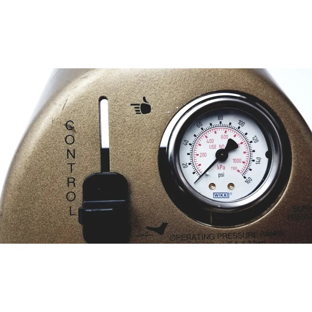 Gold-colored wika pressure gauge with black dial on white face mounted on metal housing next to control knob on midas rex legend gold pneumatic foot control unit