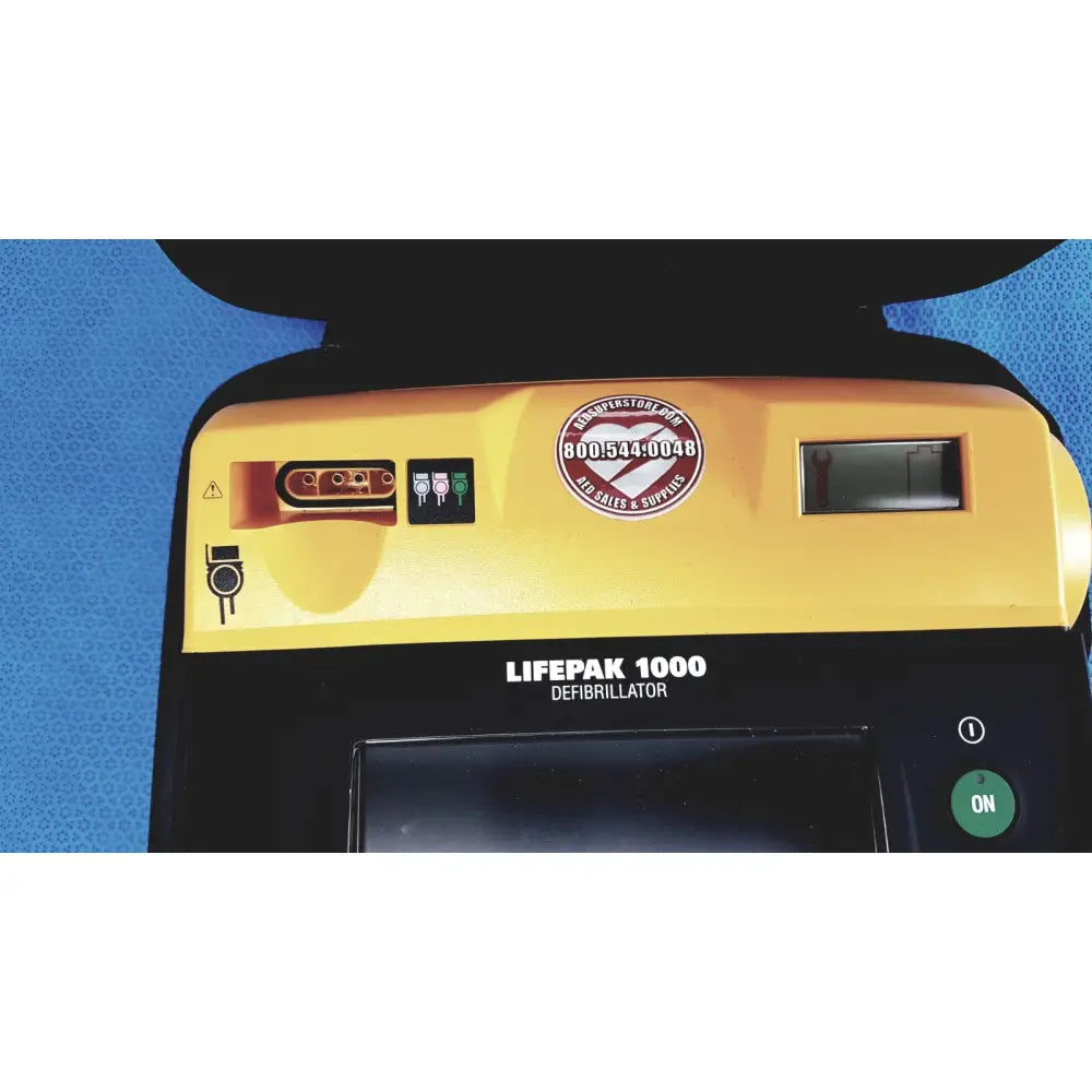 Yellow and black medtronic lifepak 1000 defibrillator with circular contact sticker requires battery and quik-pak pads reuse medical