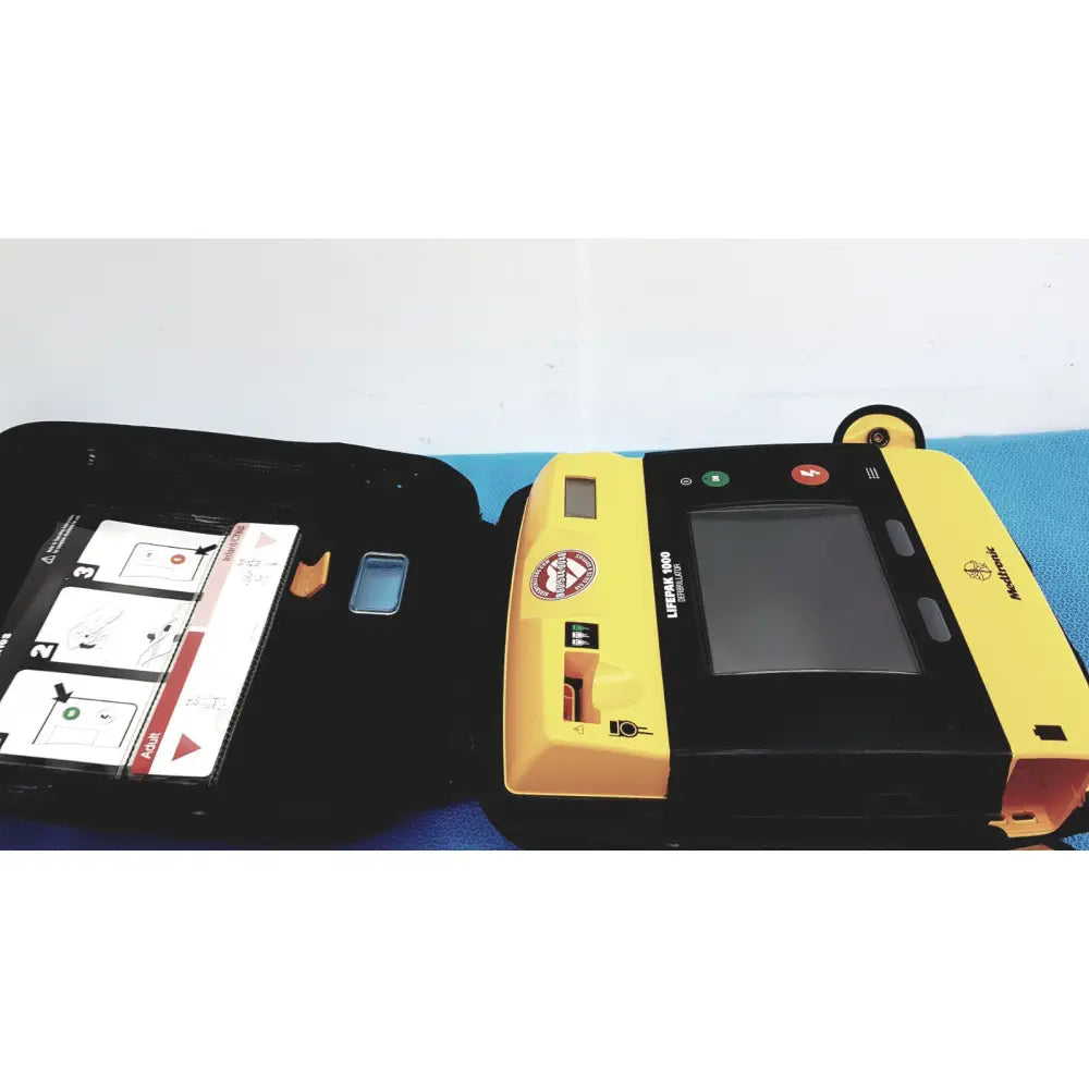 Yellow and black medtronic lifepak 1000 defibrillator with touchscreen and label in a case requiring quik-pak pads and battery for reuse medical