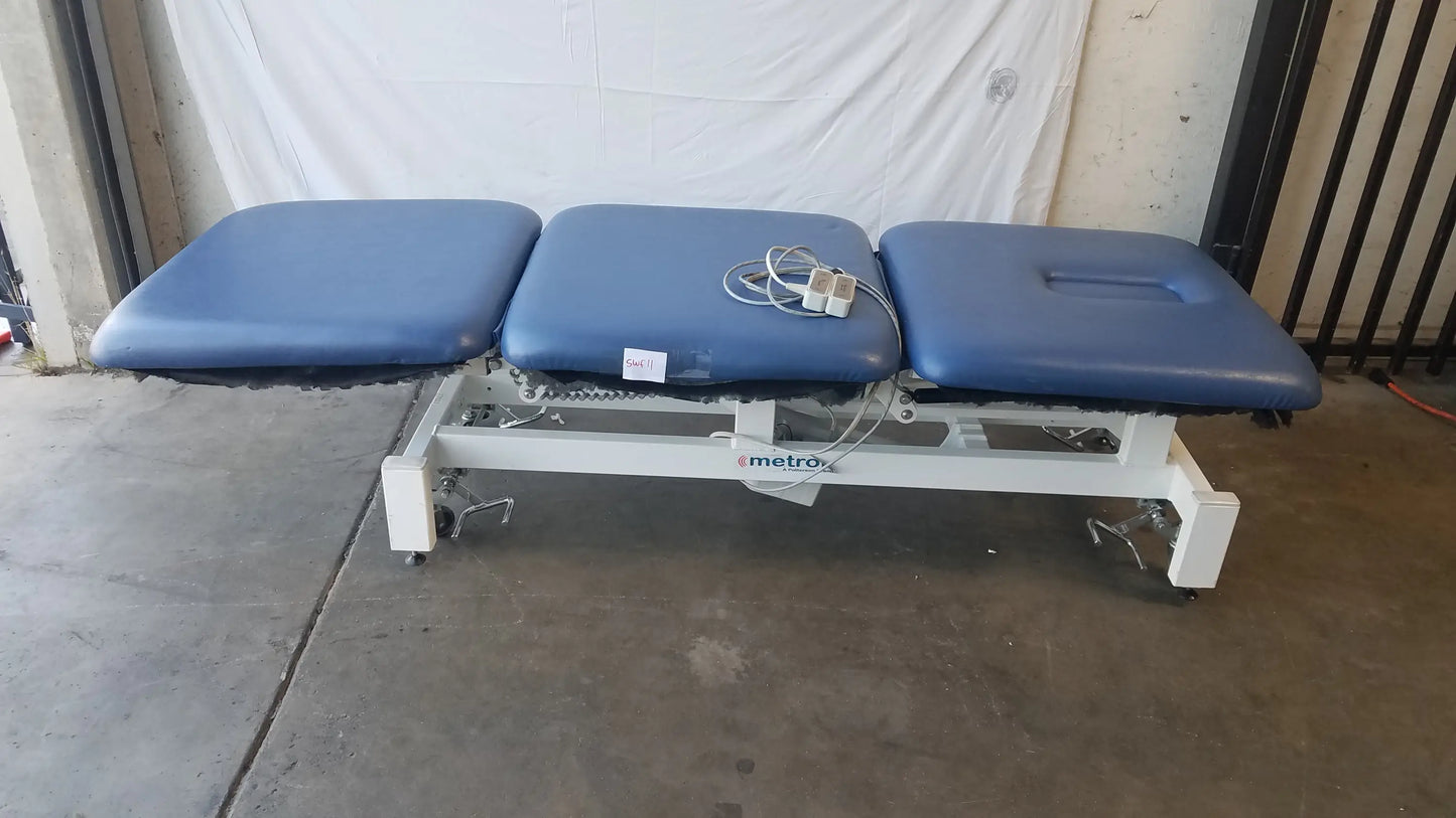 Blue three-section electric treatment table with white metal frame and casters branded metrox for medical use