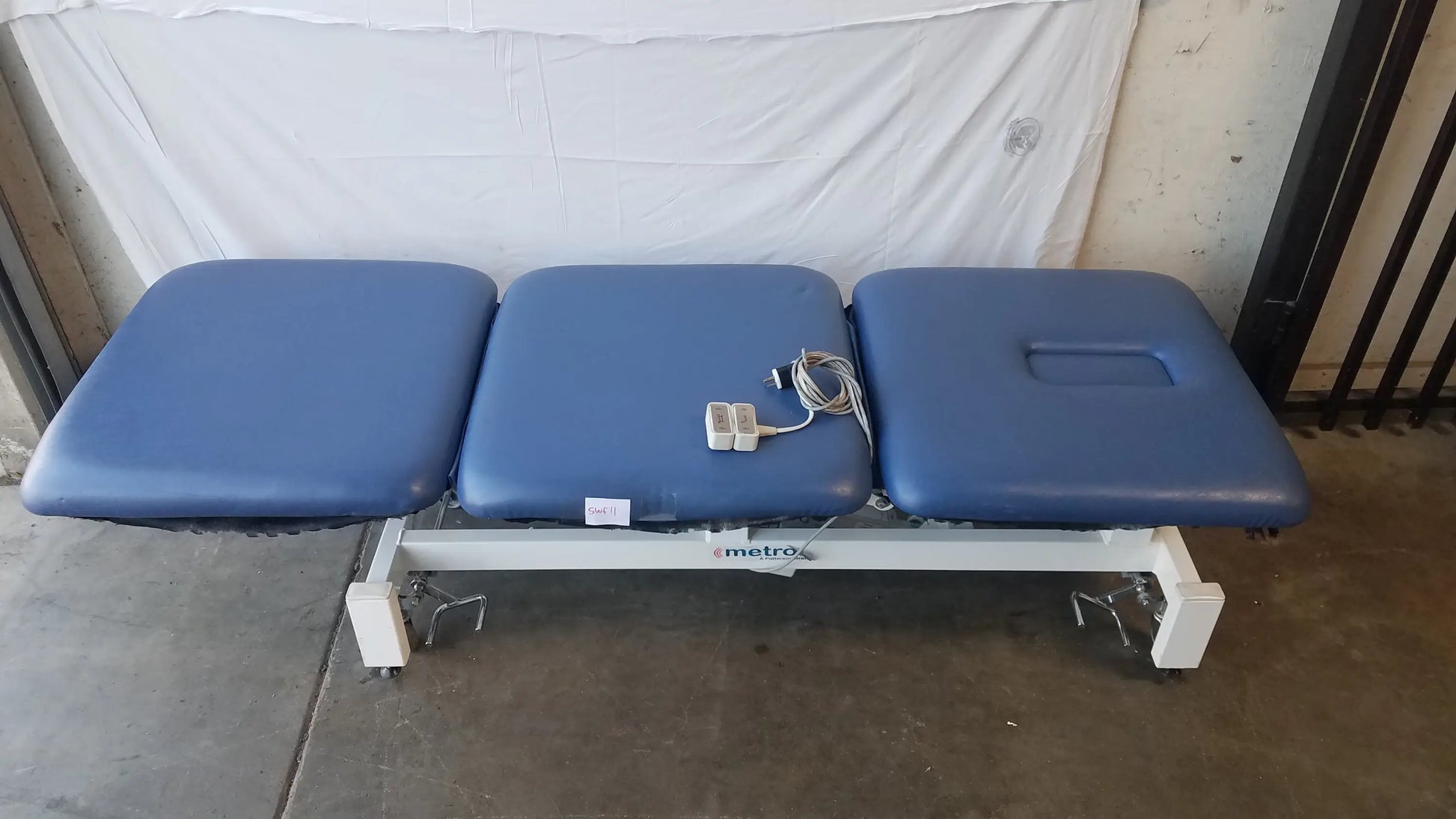 Blue three-section electric treatment table with white metal frame and casters for versatile electric treatment use