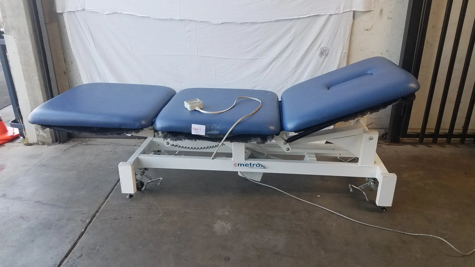Blue upholstered electric treatment table with white metal frame and casters metron 3 section electric treatment table