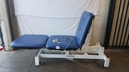 Blue upholstered metron 3-section electric treatment table with white metal frame and wheels for electric treatment
