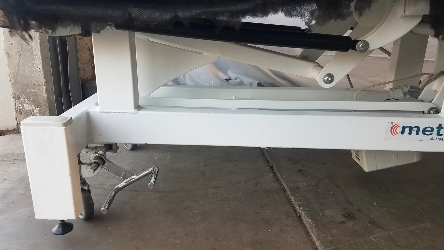 White metal treatment table frame with black hydraulic lift mechanism and met brand logo for electric treatment use