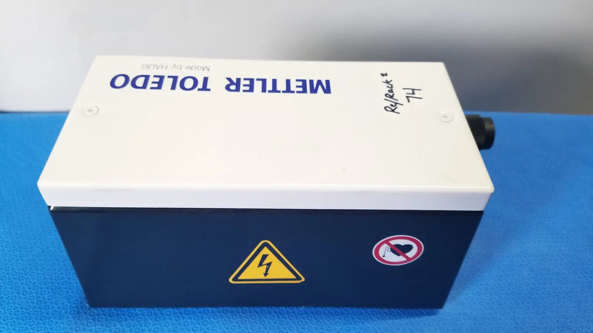 White and navy blue mettler toledo haug slc power supply box with yellow warning symbol and no heart sticker on side