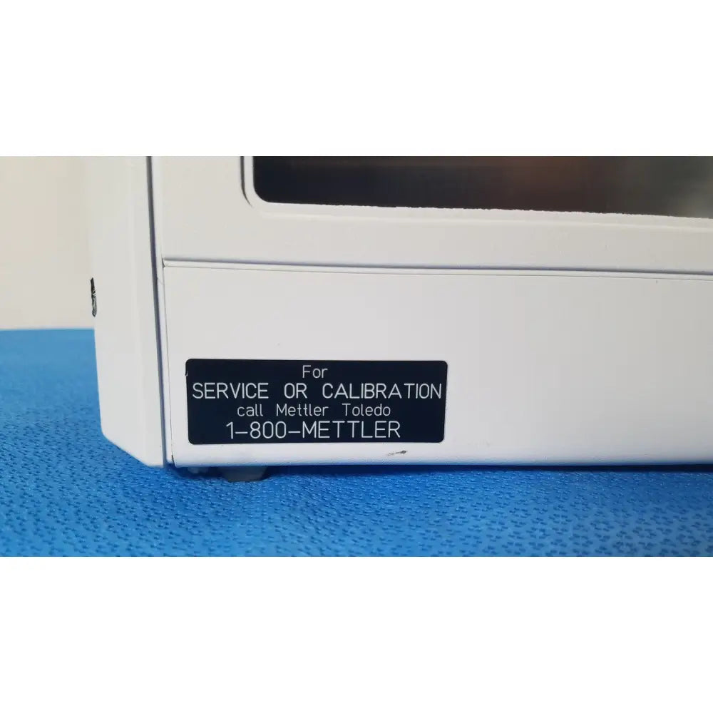 White plastic mettler toledo umx2 ultra-microbalance scale showing black label with service contact information