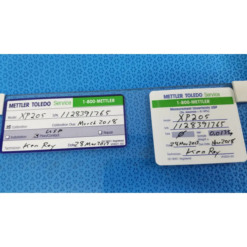 Two white service labels with green and black text on mettler toledo xp205 conducting glass draft shield product