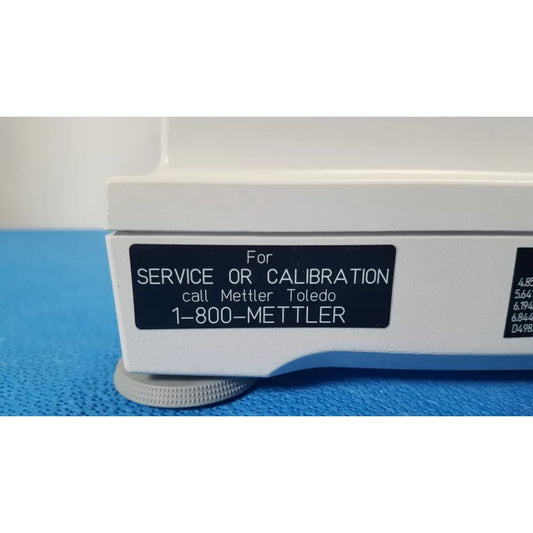White laboratory balance with black label for service or calibration call mettler toledo 1-800-mettler with silver knobs for xp5003sdr